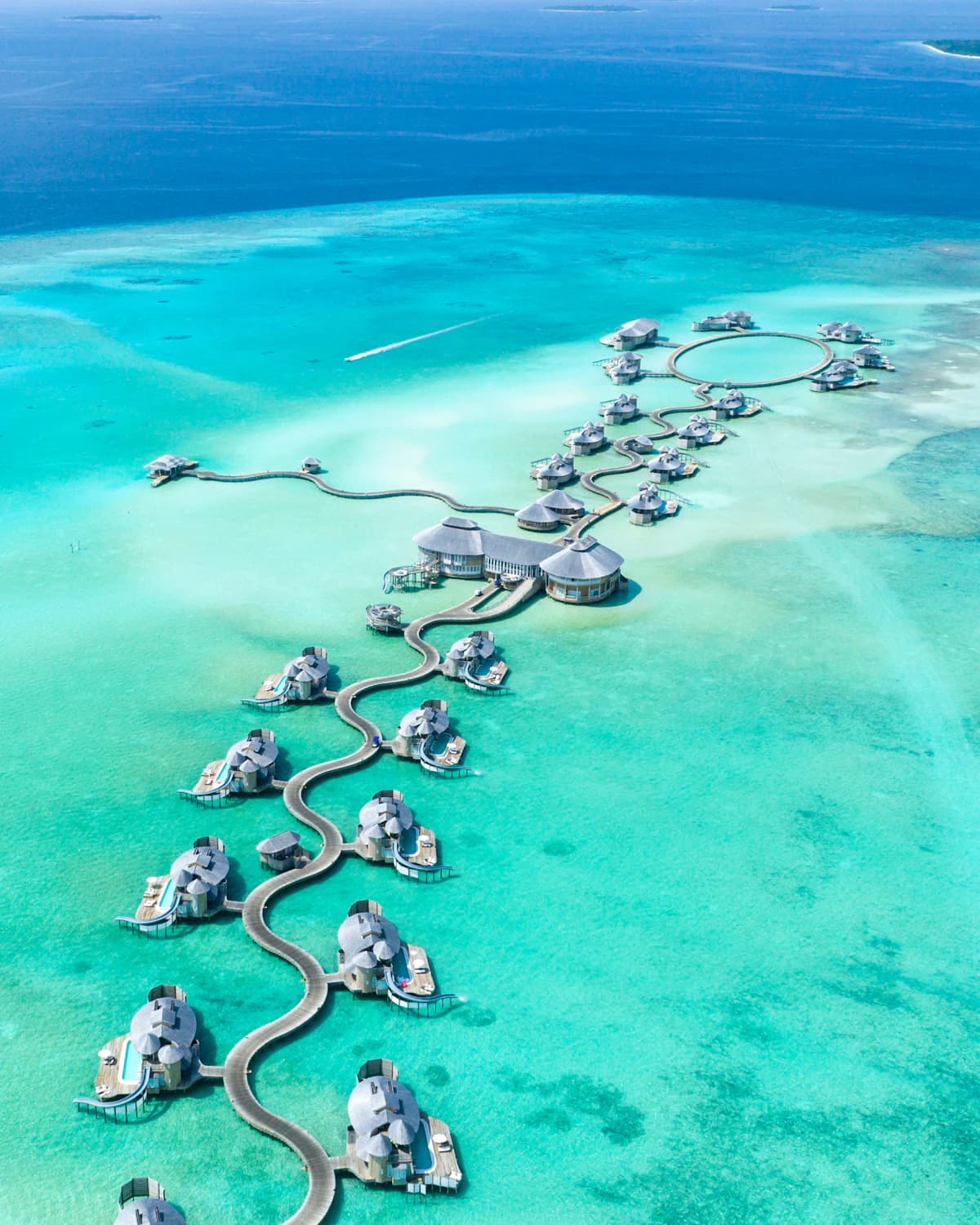 Overwater villas linked by winding walkways above a turquoise lagoon in the Maldives